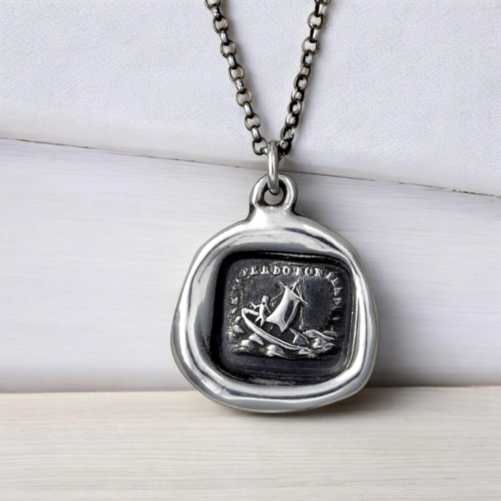 a necklace with a picture of a boat on it
