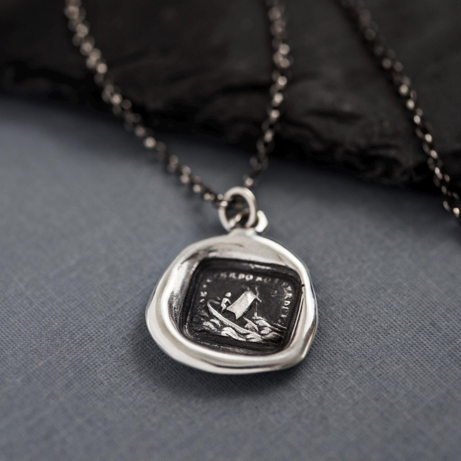 a black and white photo of a pendant on a chain